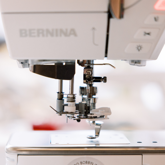BERNINA N&auml;hmaschine in Nahaufnahme mit N&auml;hfuss, Nadelbereich und N&auml;hplatte, scharfer Fokus auf der Mechanik vor unscharfem Hintergrund image number